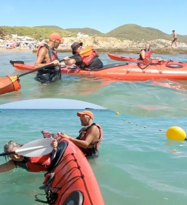 Instructores y participantes preparando kayaks rojos en la playa durante un curso de kayak de mar en Ibiza con aguas turquesas de fondo.